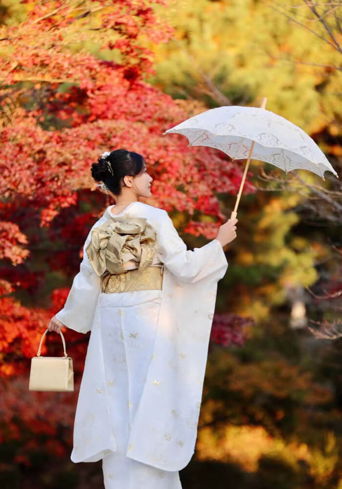 Traveler in cherry blossom pink furisode kimono taking photo under sakura trees at Maruyama Park, Kyoto spring
