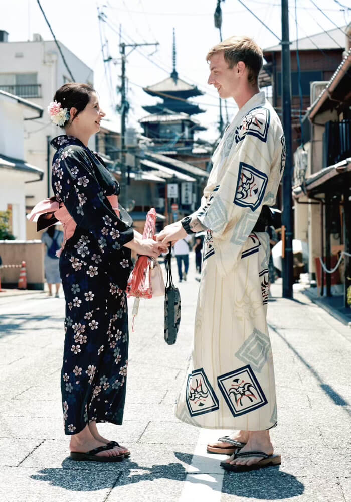 Smiling tourist in autumn-toned silk kimono holding a paper umbrella near Yasaka Shrine at sunset, Kyoto